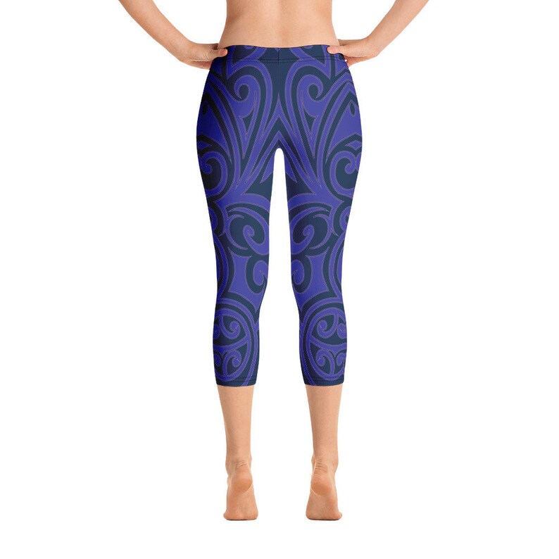 May include: Blue and navy capri leggings with a repeating, swirling pattern. The leggings are form-fitting and reach the mid-calf. The design features a symmetrical arrangement of curved lines and shapes, creating a visually appealing and dynamic look.