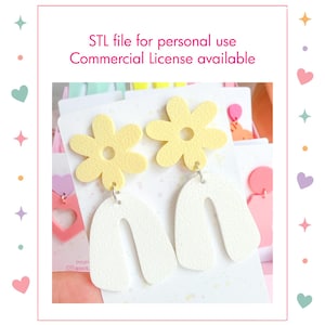Può includere: Un paio di orecchini pendenti con una parte superiore a forma di fiore giallo pallido collegata a una parte inferiore bianca a forma di arco. Il testo "STL file for personal use Commercial License available" è stampato sopra gli orecchini.