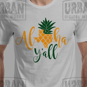 Puede incluir: Una camiseta blanca con un diseño de piña verde y amarilla en forma del estado de Texas. El texto "Aloha y'all" está escrito en verde debajo de la piña.