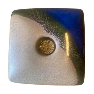 May include: Square glass flower frog with a textured, white and blue design. The top right corner is blue, transitioning to green and white. A gold-coloured floral pin frog is in the centre.