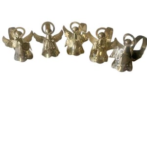 May include: Five brass angel figurines with outstretched wings. Each angel has a halo and is holding a musical instrument or object. The angels are arranged in a row against a white background.