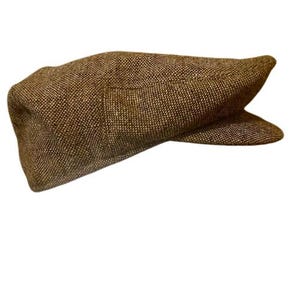 Puede incluir: Una gorra plana de tweed marrón con una visera ligeramente curvada.
