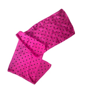 Puede incluir: Una bufanda de seda rosa con estampado de lunares negros.