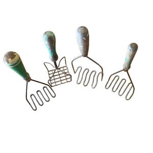 May include: Four vintage potato mashers with wooden handles and metal mashing heads. The handles are painted in shades of green and gray, showing signs of wear. One masher has a grid-style head, while the others have wavy wire designs.