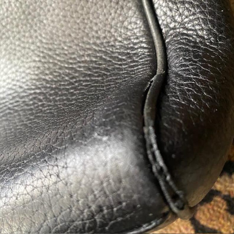 K&ouml;nnte beinhalten: Nahaufnahme von schwarzem Leder mit einer gen&auml;hten Naht. Das Leder hat eine strukturierte Maserung.