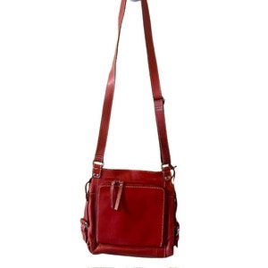 May include: A red leather crossbody bag with a flap closure and multiple pockets.