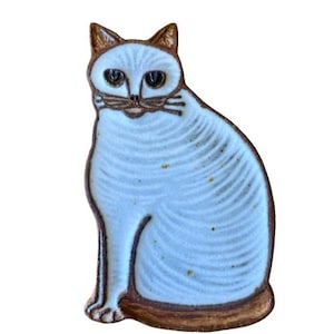 May include: A ceramic cat ornament in a seated pose. The cat features a light blue body with brown detailing on the ears, eyes, nose, and outline. The ornament has a textured surface and a charming design.