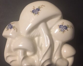 May include: White ceramic mushroom shaped planter with blue and brown floral details. The planter is made of three mushrooms clustered together.