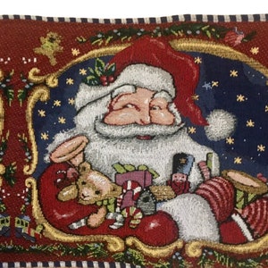 May include: A red, white, and blue tapestry featuring Santa Claus holding a teddy bear and other gifts. The background is a dark blue with white stars.