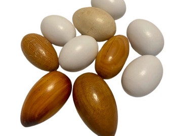 May include: A collection of wooden and white eggs, some with a smooth finish and others with a textured surface. The eggs are arranged in a star shape.