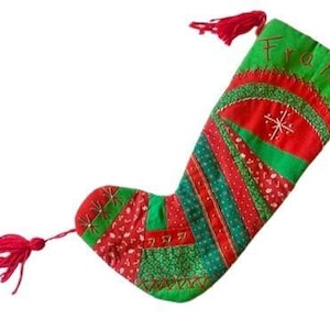 Könnte beinhalten: Ein handgefertigter Weihnachtsstrumpf mit Patchwork-Design in Rot und Grün. Der Strumpf trägt den Namen "Franz" in Grün gestickt, einen roten Quastenanhänger und ein Schneeflockenmuster. Eine festliche Weihnachtsdekoration.