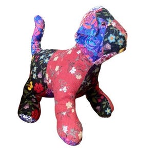 Puede incluir: Un juguete para perro de patchwork hecho de tela floral colorida. El juguete es rojo, negro, morado y azul con una variedad de patrones florales.