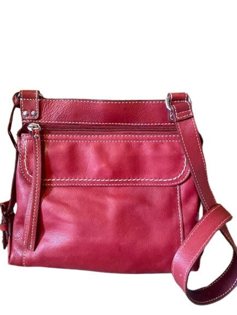 May include: A red leather crossbody bag with a white stitch detail and a silver zipper. The bag has a flap closure and a long adjustable strap.