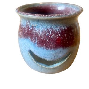 May include: A small, ceramic, blue and burgundy colored oil burner with a cut-out design.