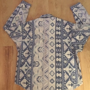 May include: A long-sleeved shirt with a white and blue geometric pattern. The pattern features a variety of shapes, including diamonds, triangles, and squares.