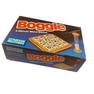 Puede incluir: Una caja del juego de palabras Boggle con el título del juego en rojo y las palabras "3-Minute Word Game". La caja presenta una bandeja amarilla de dados con letras y un reloj de arena amarillo y blanco. El logotipo de Parker Brothers es visible.