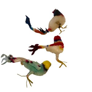 Peut inclure: Trois figurines d'oiseaux colorés avec des accents blancs, rouges, bleus, jaunes et verts. Les oiseaux ont des ailes et des queues détaillées, et sont posés en plein vol. Les figurines sont posées sur un fond blanc uni.