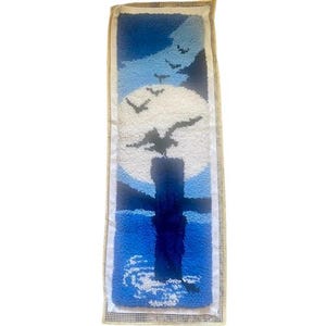 May include: A blue and white rug with a moon and birds design. The rug is made of yarn and is hand-stitched.