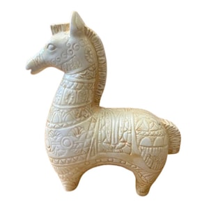 Puede incluir: Una figurita de caballo de cerámica blanca con intrincados detalles tallados. El caballo tiene una larga melena y cola y está de pie sobre sus cuatro patas.