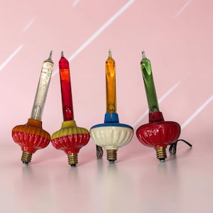 May include: Four vintage bubble light bulbs with metallic screw bases and clips. The bulbs feature clear, red, orange, and green glass tubes atop ribbed, colorful bases in red, yellow, blue, and red, designed for decorative holiday lighting.