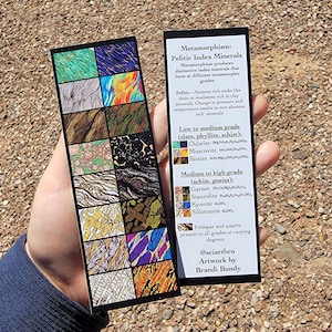 Peut inclure: Deux marque-pages noirs avec des illustrations colorées de minéraux métamorphiques. L'un présente 16 échantillons de minéraux, l'autre fournit des informations sur les minéraux indices pélitiques, avec texte de @sciartbro et œuvre de Brandi Bundy.