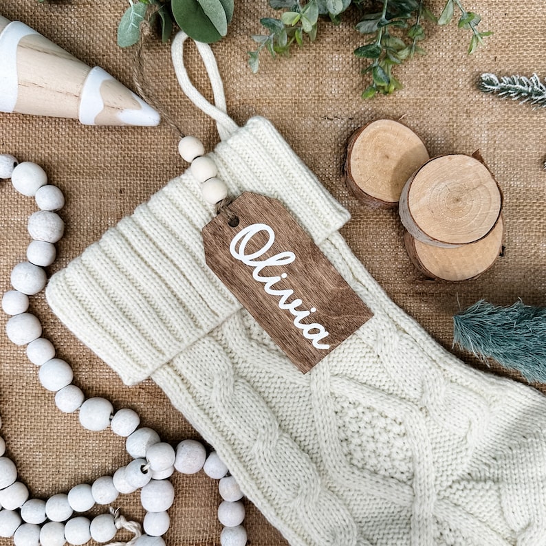 May include: White knitted Christmas stocking with a wooden tag that says "Olivia".