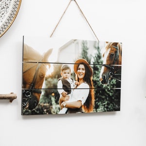 May include: A wooden sign with a photo of a woman and a child holding a horse. The photo is split into three horizontal sections, creating a rustic look.