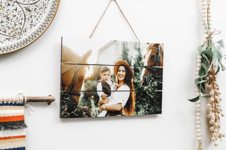 May include: A wooden sign with a photo of a woman and a child holding a horse. The photo is split into three horizontal sections, creating a rustic look.