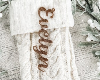 May include: A white knitted Christmas stocking with a gold glitter name tag that says "Evelyn".