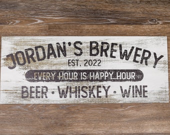 May include: White wooden sign with black text that reads "JORDAN'S BREWERY EST. 2022 EVERY HOUR IS HAPPY HOUR BEER WHISKEY WINE".