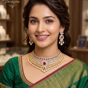 May include: A woman wearing a gold and pearl necklace with ruby and emerald accents, and matching earrings. The necklace is a choker style. The woman is wearing a green sari with gold trim. The text "Indian Designs" is in the upper left corner.