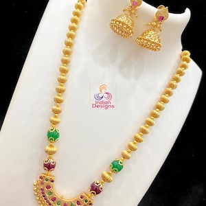 May include: A gold necklace with green and pink beads and a pendant with a crescent moon design. The necklace is paired with matching earrings.