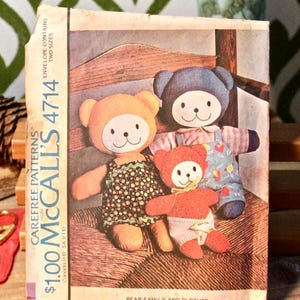 May include: A vintage McCall's 4714 sewing pattern envelope featuring an illustration of three stuffed bears in clothing. The envelope includes the text Carefree Patterns, $1.00, and Bear Family and Clothes. The design shows two larger bears and one small bear.