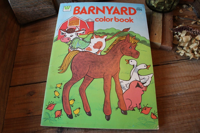 May include: A vintage coloring book with a colorful illustration of a brown horse, a cow, a chicken, and two geese. The book cover features the title "BARNYARD color book" and a red barn.