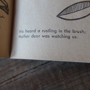 May include: A page from a children's book with black and white illustrations. The text reads: "We heard a rustling in the brush; Mother deer was watching us."