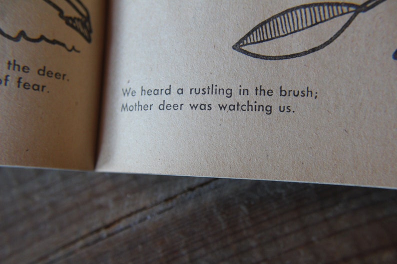 May include: A page from a children's book with black and white illustrations. The text reads: "We heard a rustling in the brush; Mother deer was watching us."