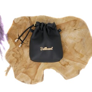 May include: A small black leather drawstring bag with a gold zipper and the word "Bellami" written in gold lettering.