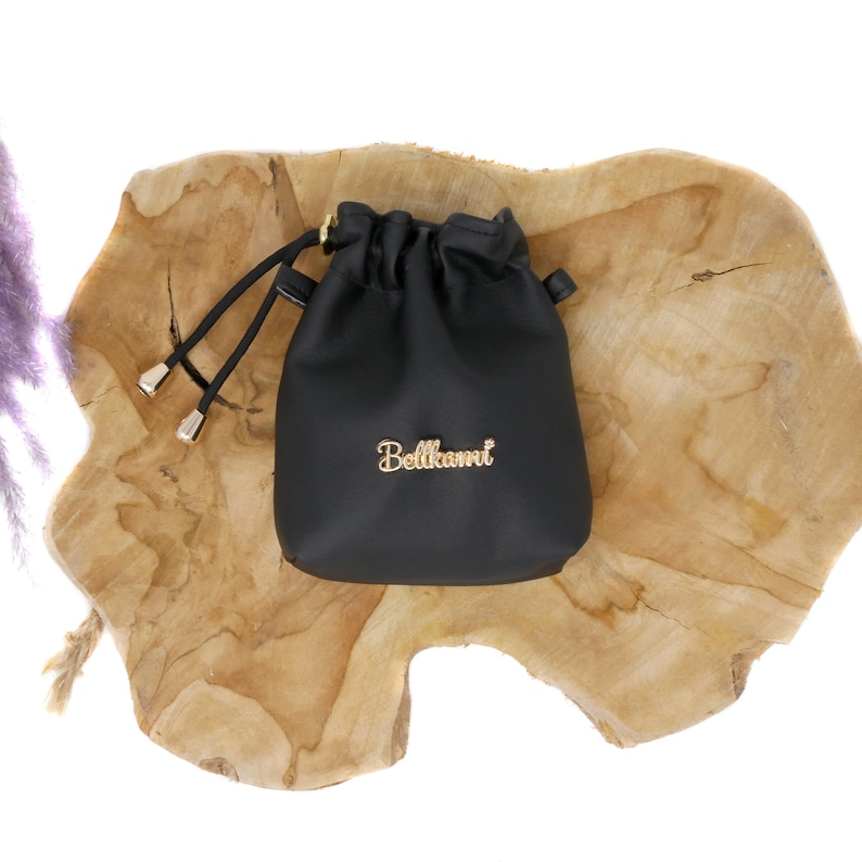 May include: A small black leather drawstring bag with a gold zipper and the word "Bellami" written in gold lettering.