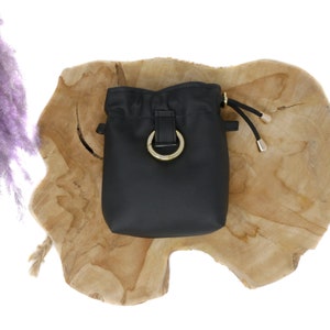 May include: Black drawstring bucket bag with a gold ring closure and a gold drawstring toggle.