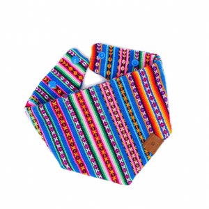 May include: A blue and multi-colored striped bandana with a brown leather patch. The bandana has blue snap buttons on the edges.