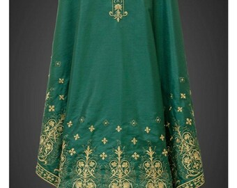 May include: Emerald green liturgical vestment with gold embroidered cross and floral patterns. The vestment features intricate detailing along the edges and a white undergarment peeking from the bottom. The design is symmetrical and formal.