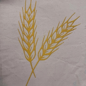 Peut inclure: Gros plan sur un tissu blanc avec un motif brodé jaune de deux épis de blé qui se croisent. Le motif de blé est détaillé avec des grains individuels et des lignes fines, créant un aspect texturé.