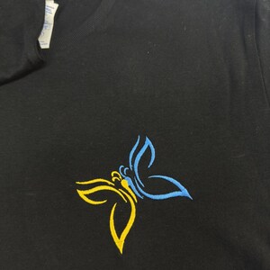 May include: Black t-shirt with a yellow and blue butterfly design.