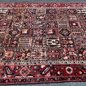 May include: A red, blue, and cream colored Persian rug with a patchwork design. The rug has a detailed floral pattern and a border with a geometric design.