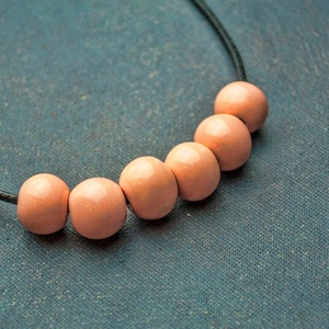May include: A necklace with a black cord and six peach-coloured wooden beads.