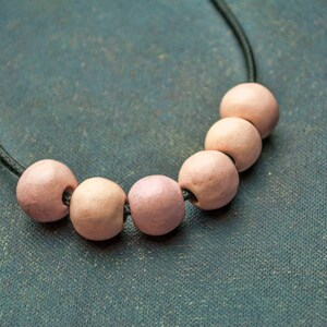 May include: A necklace with a black cord and six pink ceramic beads.