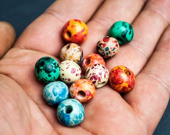 May include: A collection of colorful wooden beads with speckled paint patterns. The beads are round and have a hole in the center.