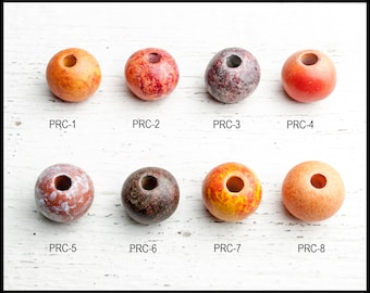 May include: Eight round wooden beads with different patterns and colors. The beads are arranged in two rows of four. The beads are all about 1 inch in diameter. The beads are made of wood and have a natural finish. The beads are perfect for making jewelry or other crafts.