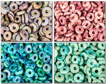 May include: A close-up of four groups of colorful donut-shaped beads. The beads are made of stone and have a speckled pattern. The colors are blue, green, pink, and brown.