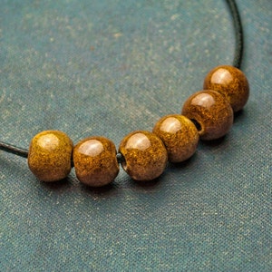 May include: A necklace with six brown wooden beads on a black cord.